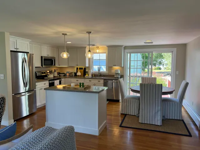 a kitchen with granite countertop a refrigerator a stove a dining table and chairs