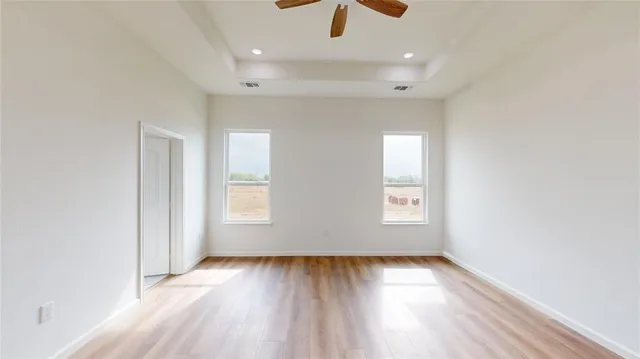 an empty room with wooden floor and windows