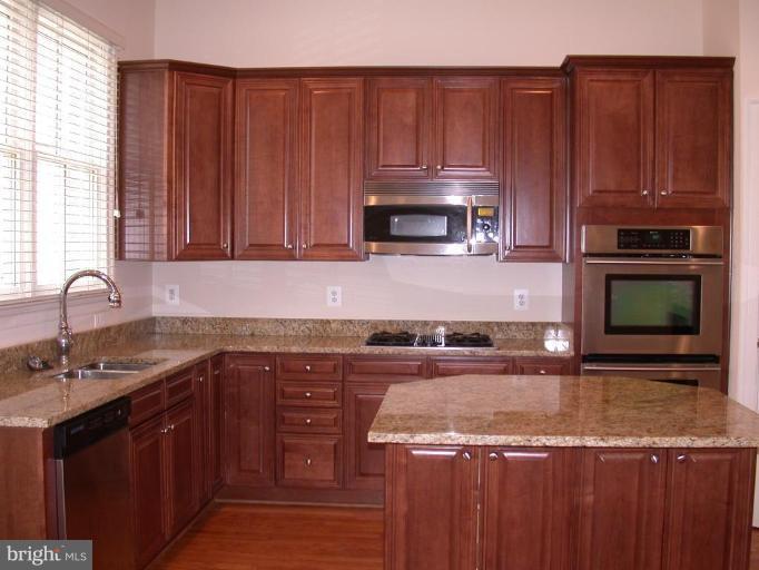 1730 Carpenter Road Alexandria, VA 22314 - Photo 3 of 20 a kitchen with granite countertop wooden cabinets and a stove top oven