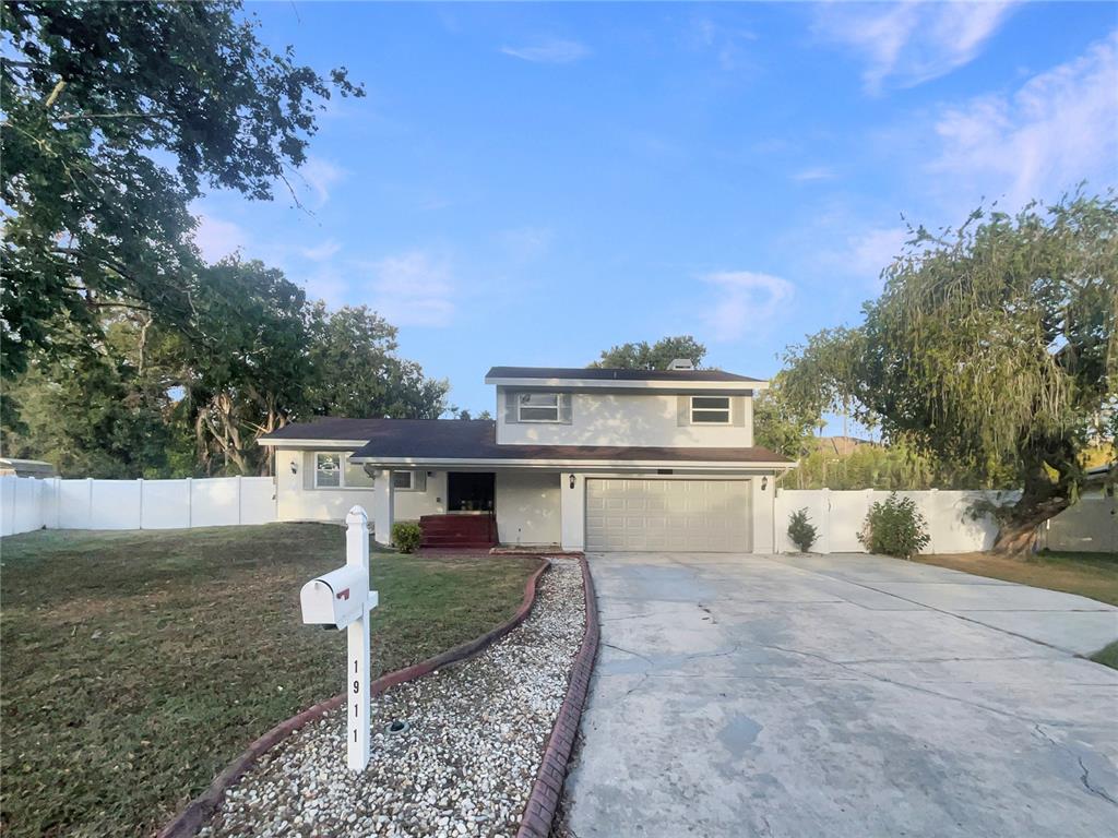 a view of a white house next to a yard with big trees