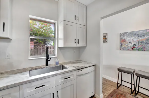 a kitchen with white cabinets and window