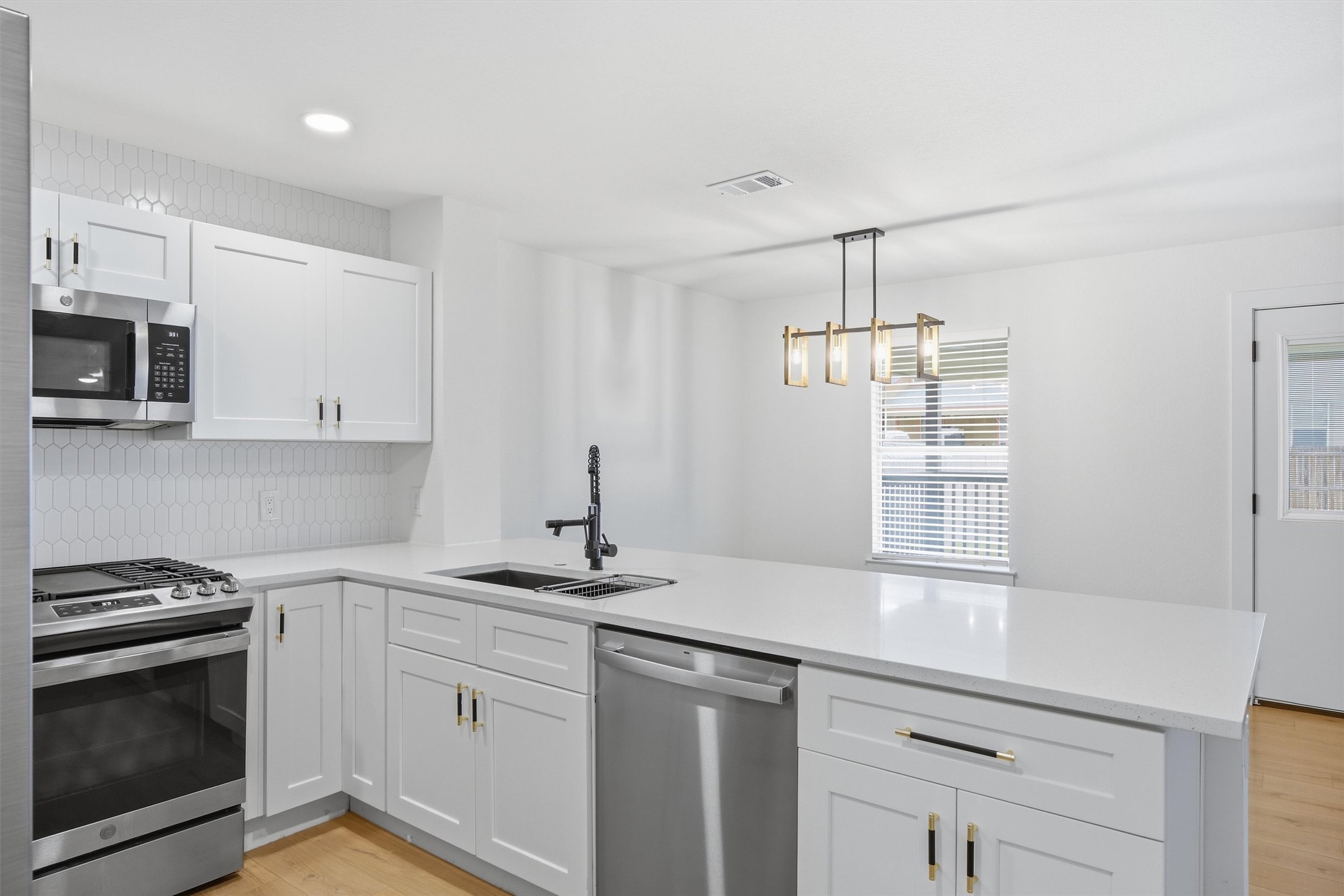 6708 Panda Royle Drive Del Valle, TX 78617 - Photo 15 of 40 a kitchen with stainless steel appliances granite countertop a sink dishwasher a stove and a microwave oven with white cabinets