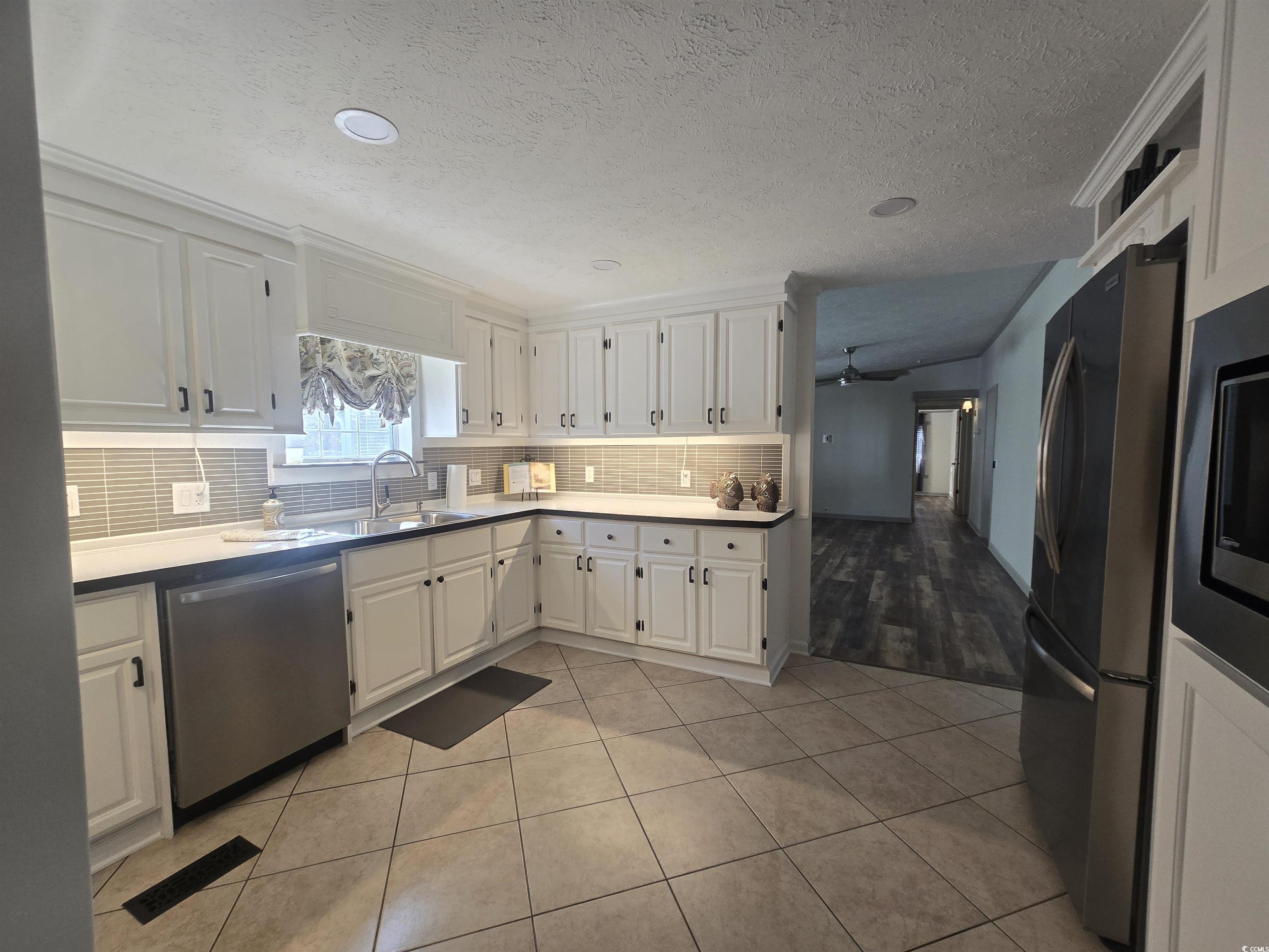 359 Lagoon Circle Murrells Inlet, SC 29576 - Photo 23 of 39 Kitchen with white cabinetry, appliances with stainless steel finishes, tasteful backsplash, light tile patterned floors, and a textured ceiling
