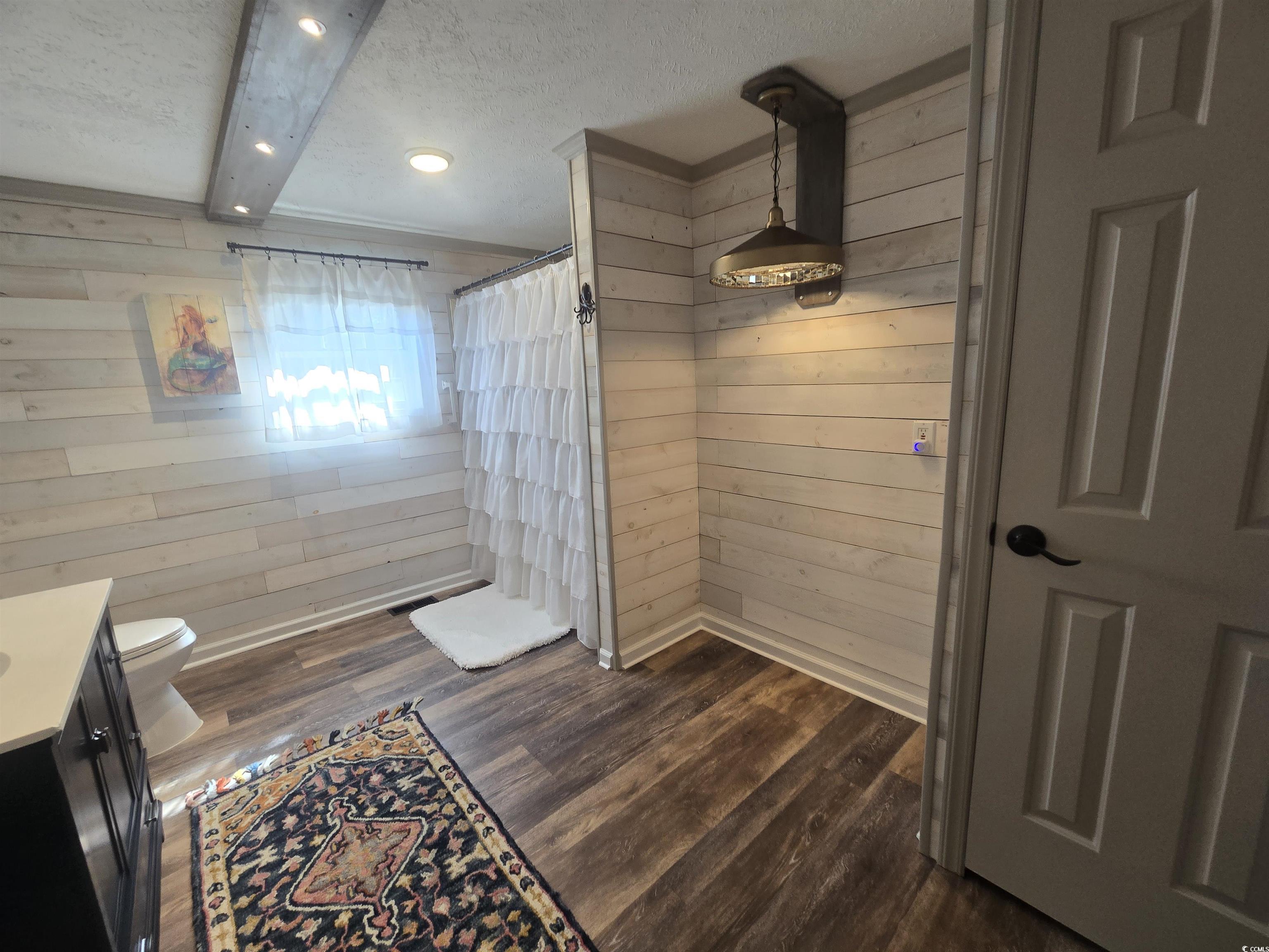 359 Lagoon Circle Murrells Inlet, SC 29576 - Photo 33 of 39 Bathroom featuring wooden walls, vanity, a textured ceiling, a shower with shower curtain, and dark wood finished floors