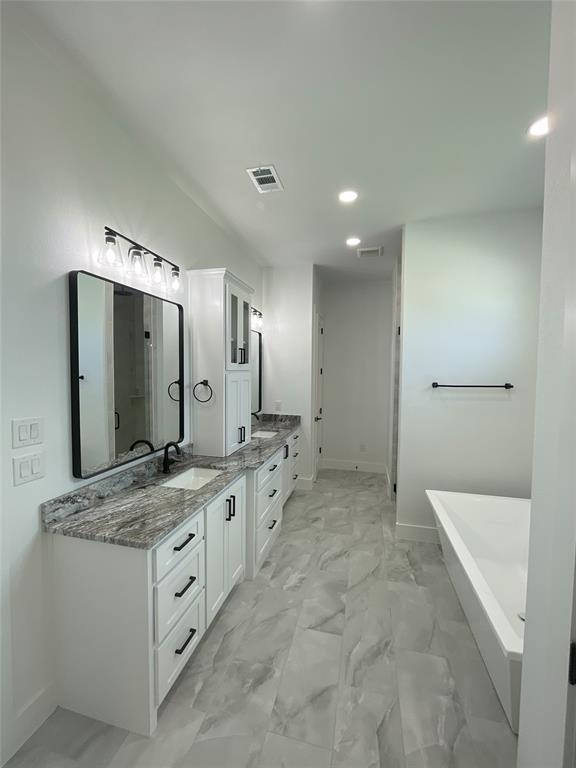 1484 Dixie Road Whitesboro, TX 76273 - Photo 6 of 18 a bathroom with a granite countertop sink a large mirror and a bathtub