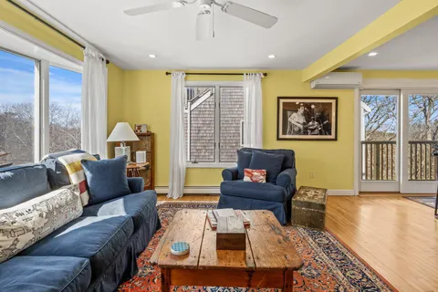 a living room with furniture two window and a wooden floor