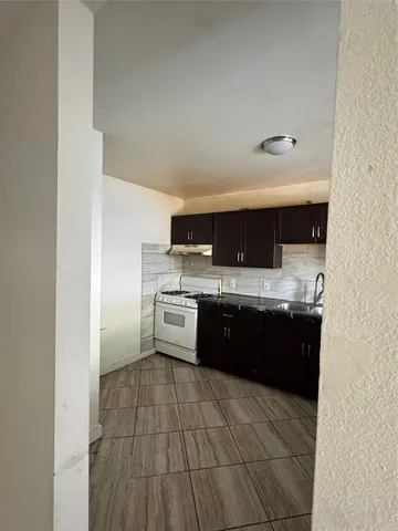 a large white kitchen with a sink and dishwasher a stove top oven with wooden floor