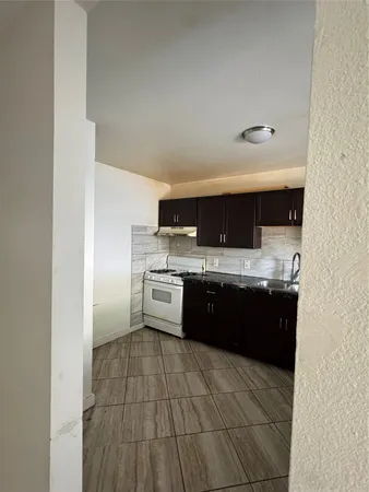 a large white kitchen with a sink and dishwasher a stove top oven with wooden floor