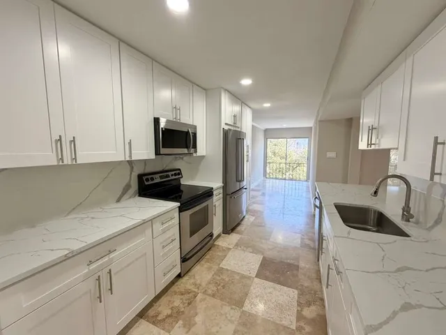 a kitchen with granite countertop white cabinets and sink