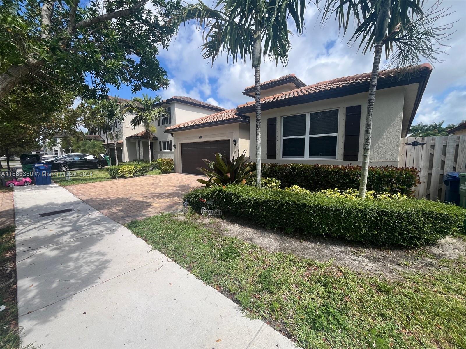 11879 Southwest 253rd Terrace Homestead, FL 33032 - Photo 3 of 26 a front view of a house with a garden and palm trees