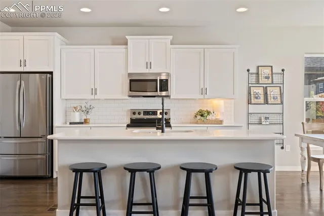 a kitchen with stainless steel appliances a table chairs refrigerator and microwave