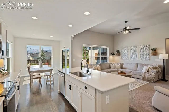 a large living room with stainless steel appliances kitchen island granite countertop a large window and a couch