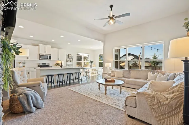 a living room with furniture kitchen view and a chandelier