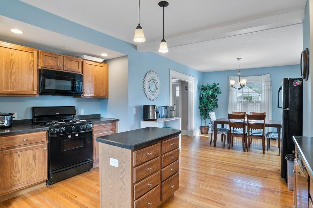 128 Shawmut Street Springfield, MA 01108 - Photo 17 of 39 a kitchen with stainless steel appliances granite countertop a stove top oven a sink a dining table and chairs with wooden floor