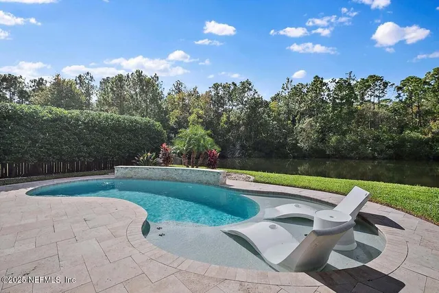 a view of swimming pool with seating space and trees in the background
