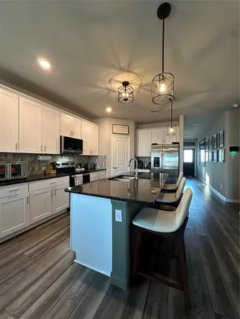 a kitchen with stainless steel appliances kitchen island granite countertop a sink a stove and cabinets