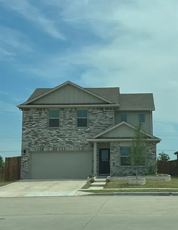 a view of a house with a small yard and large tree