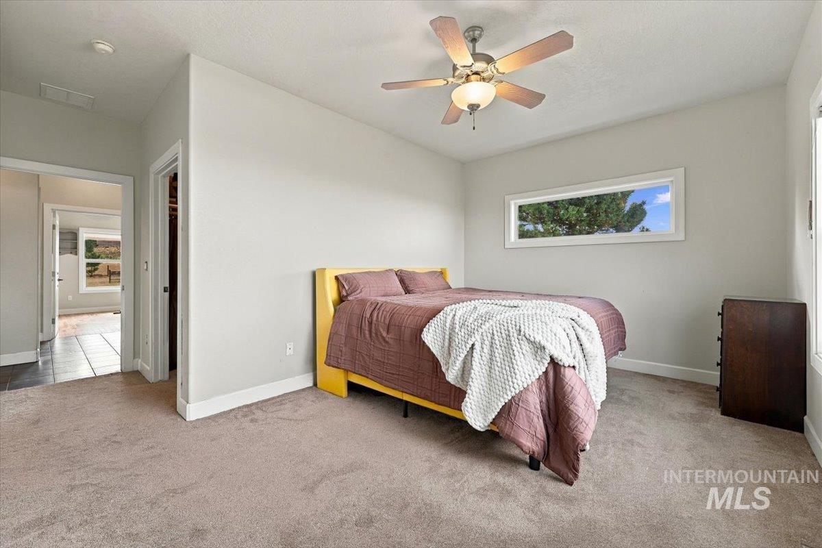 18026 Briar Creek Road Murphy, ID 83650 - Photo 22 of 50 Spacious room with large windows, light-colored carpeting, and a ceiling fan