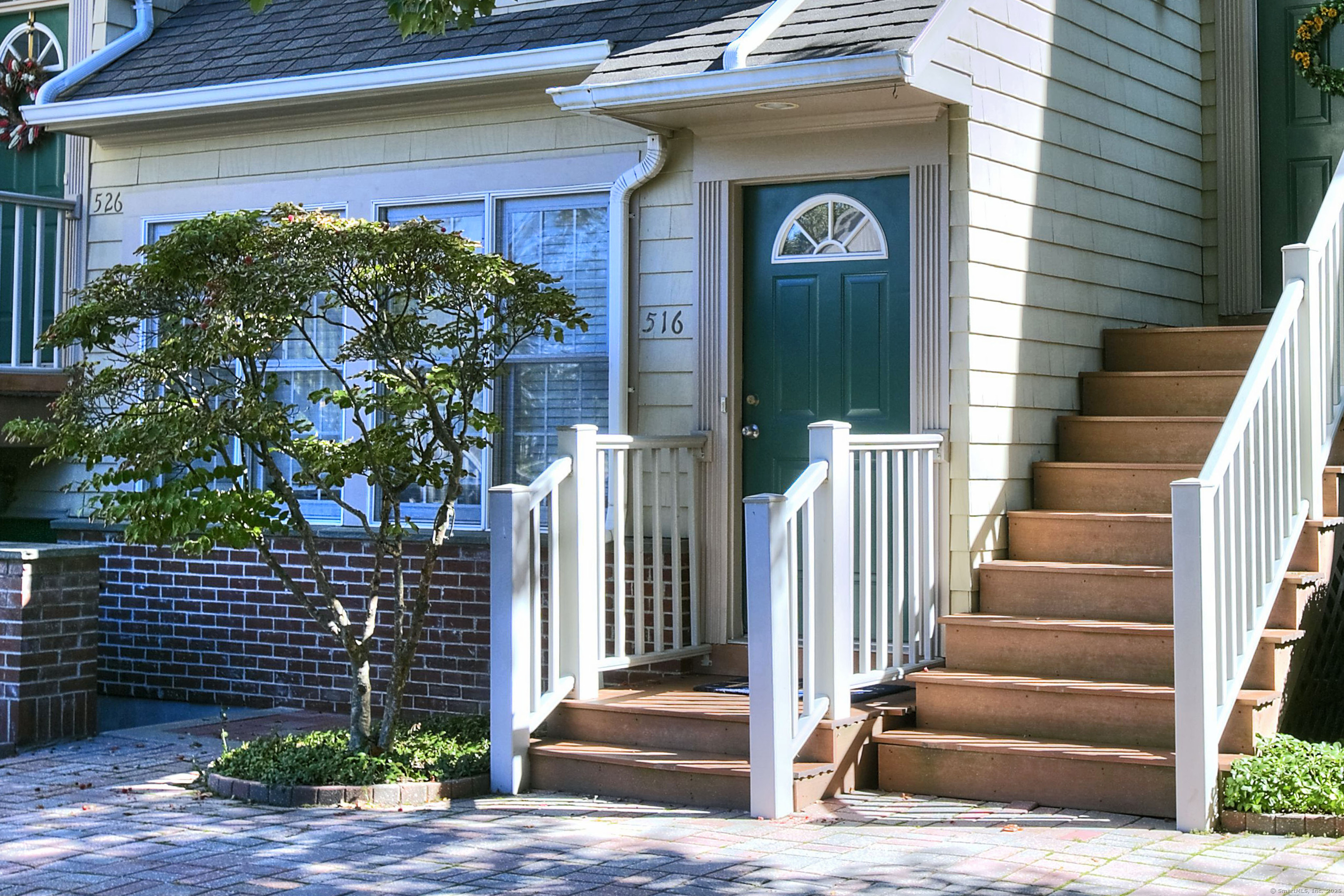a view of a brick house with a small yard and wooden floor and fence and a potted plant