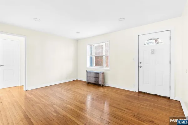 an empty room with wooden floor cabinet and windows