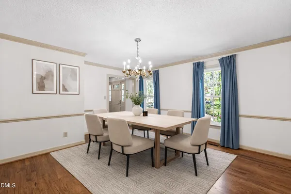 an empty room with wooden floor chandelier and windows