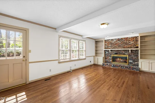 a view of an empty room with window and wooden floor