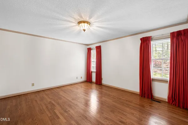 a view of an empty room with wooden floor and closet