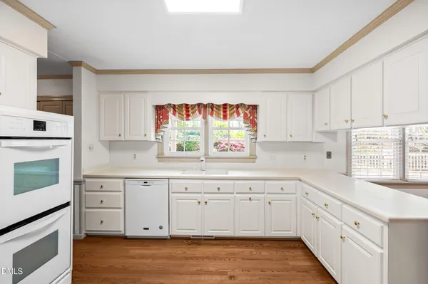 a kitchen with a sink cabinets wooden floor and stainless steel appliances
