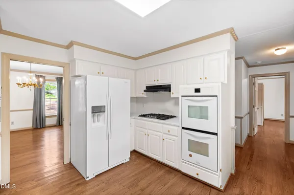 a kitchen with cabinets wooden floor and stainless steel appliances