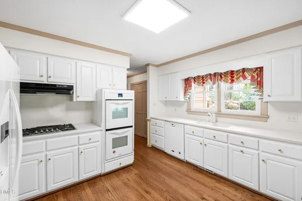 a kitchen with wooden floors and white cabinets