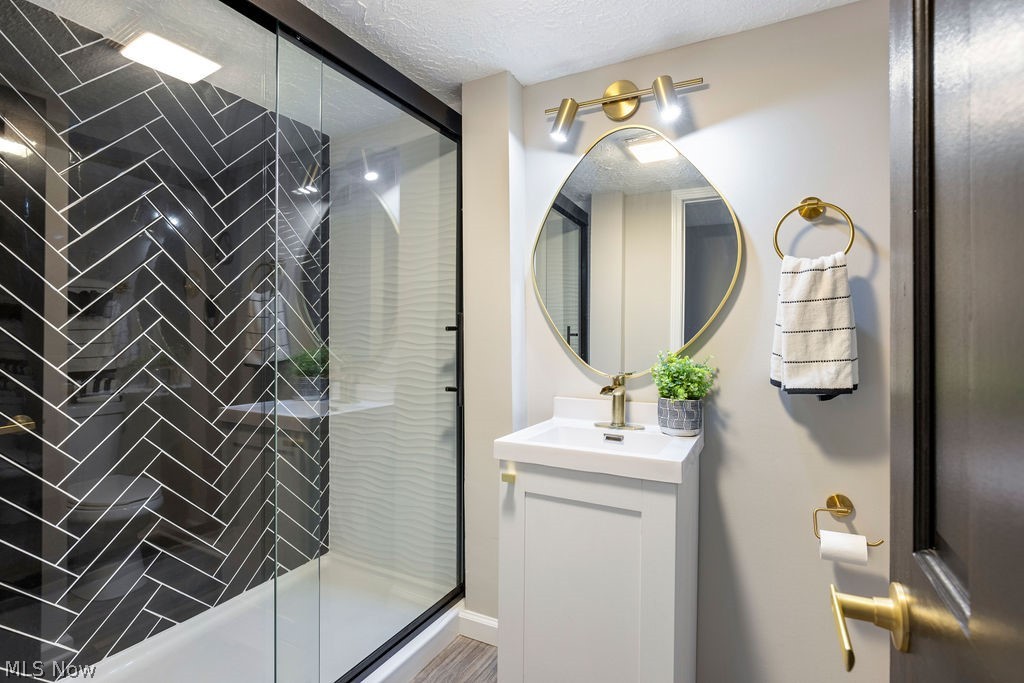 9620 David Road Garfield Heights, OH 44125 - Photo 24 of 36 Bathroom with vanity, a shower with door, and a textured ceiling