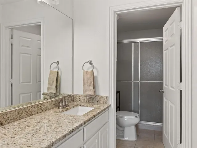a bathroom with a granite countertop sink toilet and shower