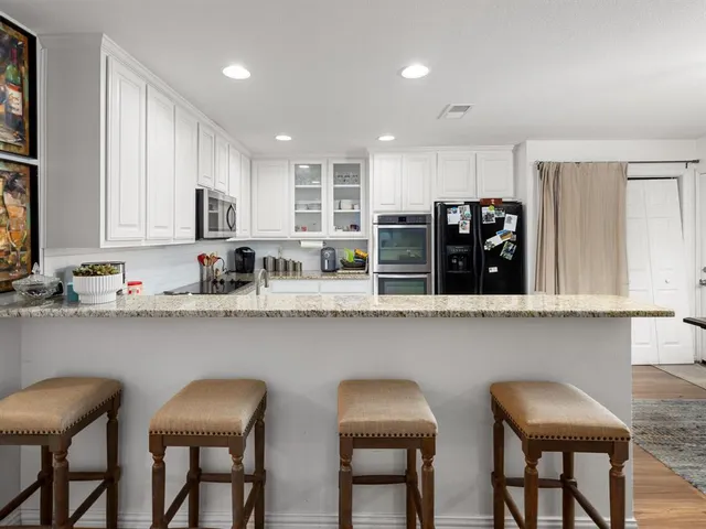 a kitchen with white cabinets and chair