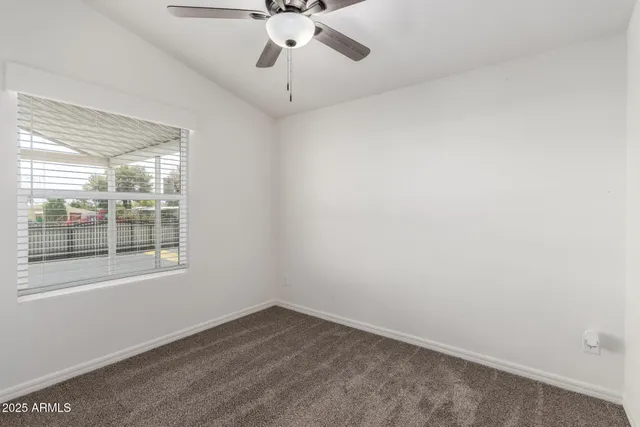 an empty room with a window and a fan