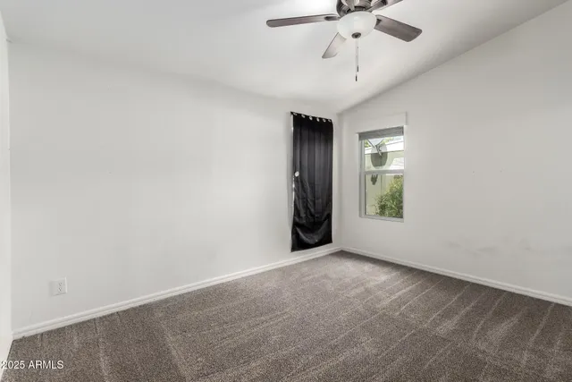 an empty room with a ceiling fan and window