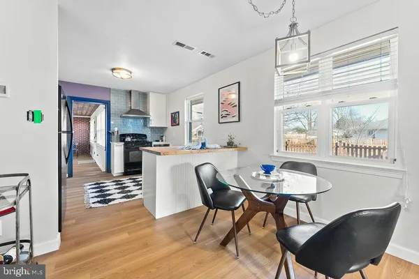 a kitchen with stainless steel appliances kitchen island granite countertop a dining table chairs and a refrigerator