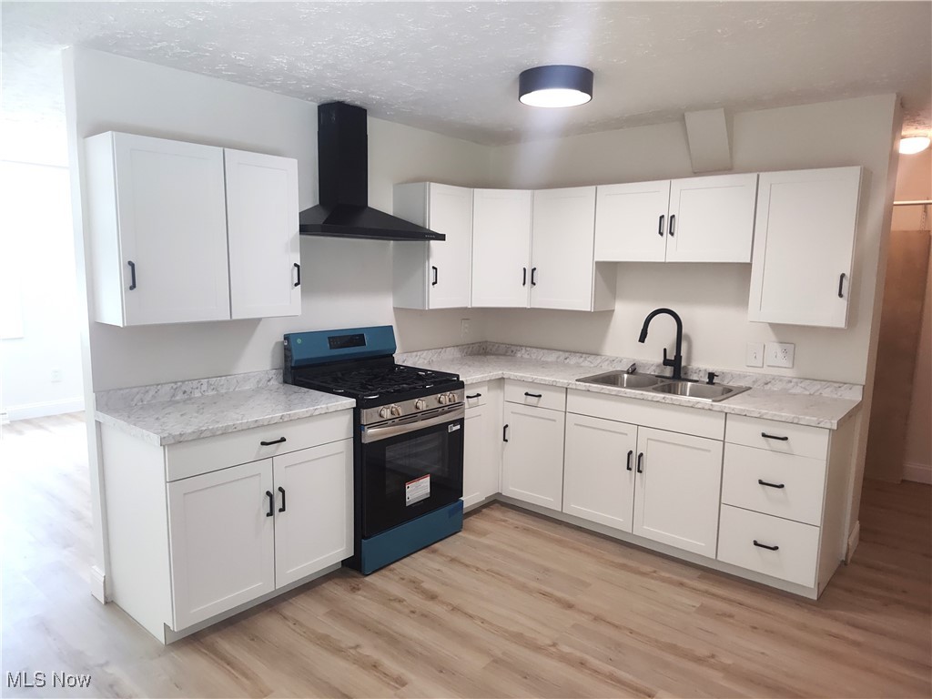8016 Ninevah Road Geneva, OH 44041 - Photo 22 of 45 Kitchen featuring stainless steel range with gas cooktop, white cabinetry, wall chimney range hood, and a textured ceiling