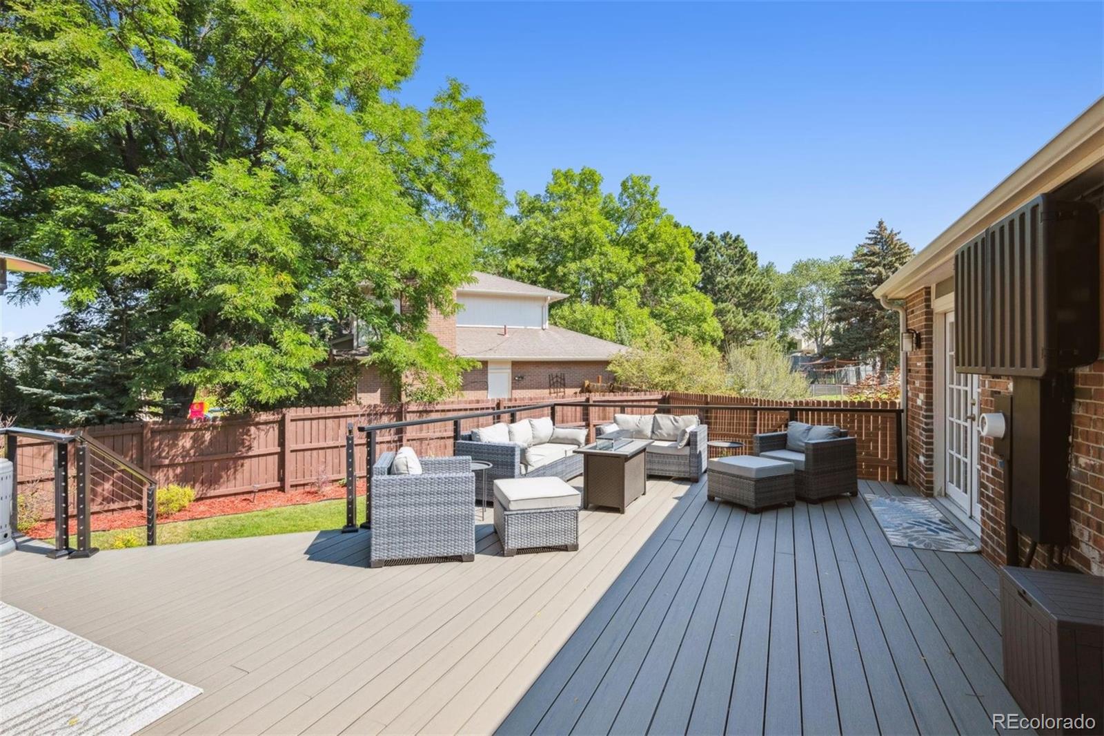 7659 South Fillmore Way Centennial, CO 80122 - Photo 33 of 45 a view of a patio with couches and table and chairs with wooden floor and fence