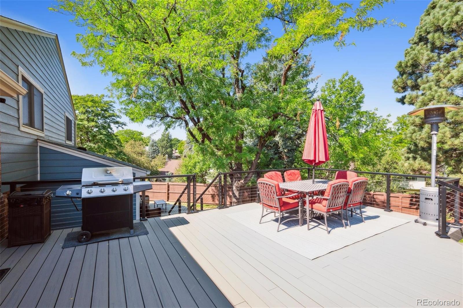 7659 South Fillmore Way Centennial, CO 80122 - Photo 34 of 45 a roof deck with table and chairs a barbeque with wooden floor and fence