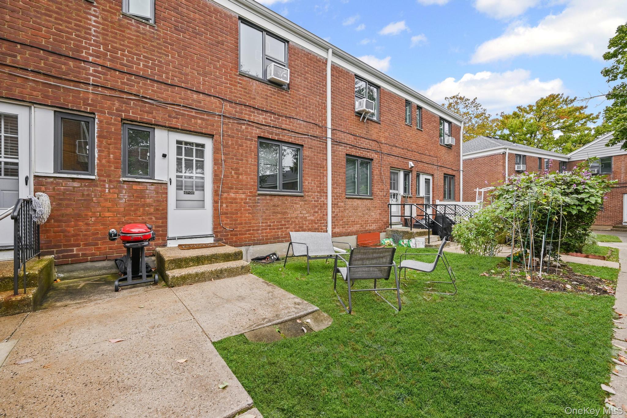 67-09 218th Street, Unit DUPLEX Queens, NY 11364 - Photo 13 of 22 a view of a brick house with a yard chairs and table in a patio