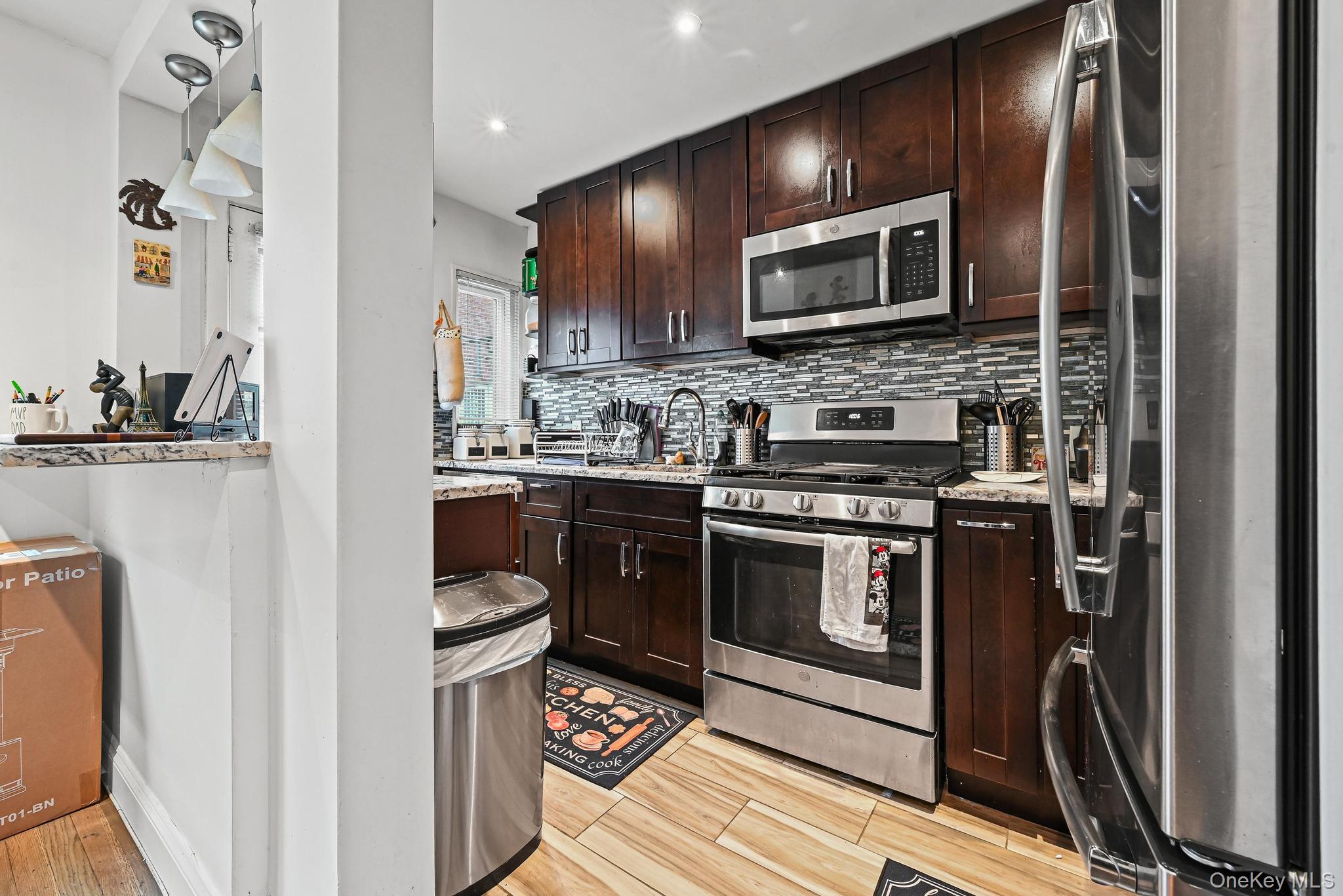 67-09 218th Street, Unit DUPLEX Queens, NY 11364 - Photo 6 of 22 a kitchen with stainless steel appliances kitchen island granite countertop a stove a sink and a microwave
