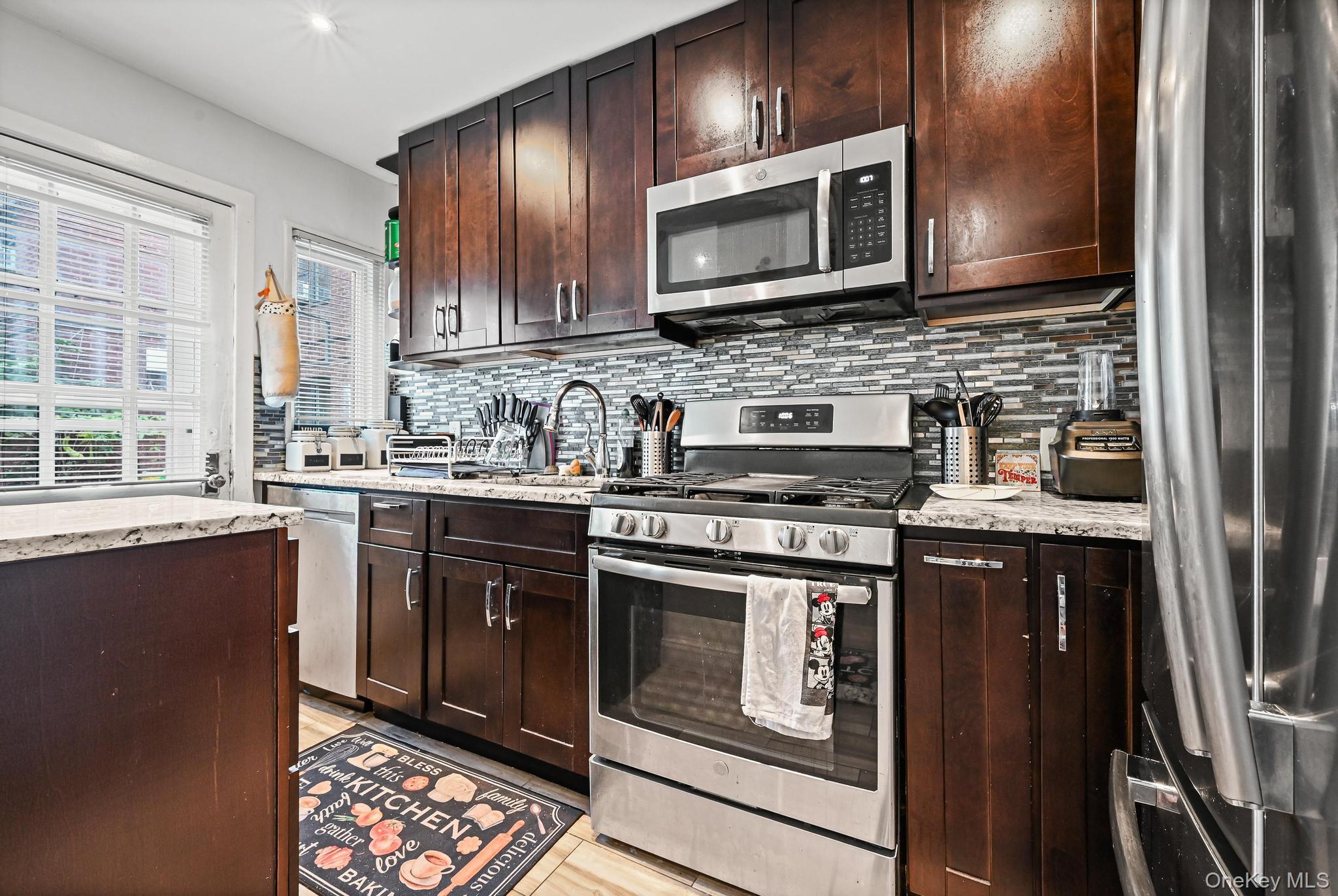 67-09 218th Street, Unit DUPLEX Queens, NY 11364 - Photo 7 of 22 a kitchen with stainless steel appliances granite countertop a stove sink microwave and cabinets