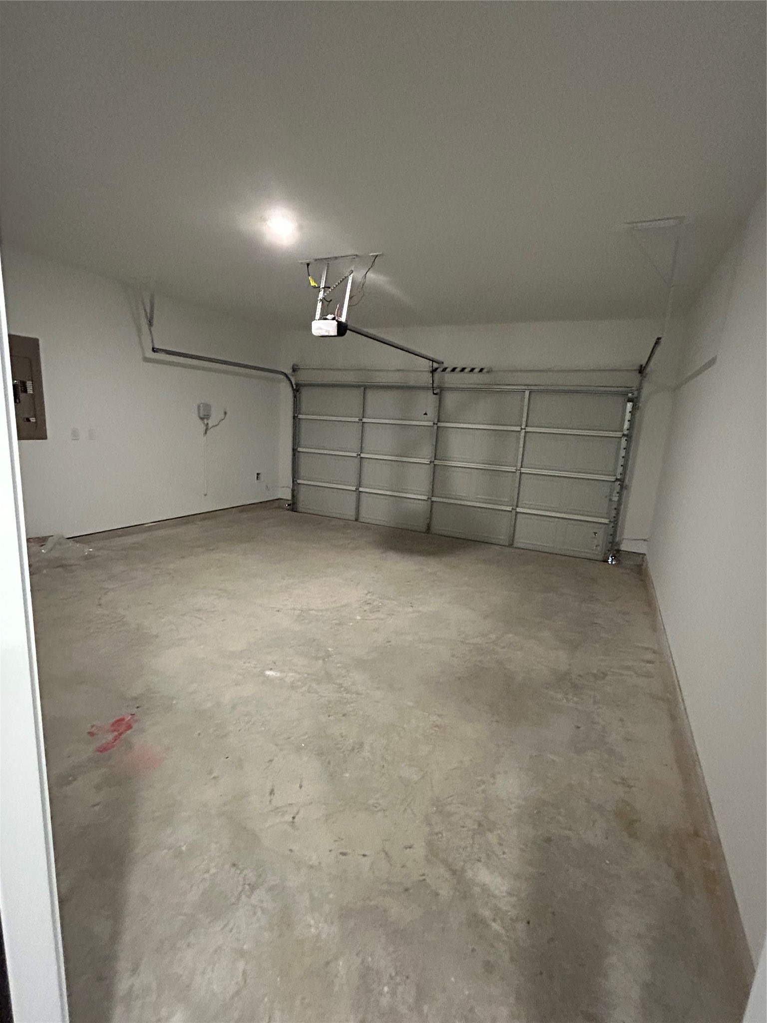 26419 Virginia Wild Rye Lane Katy, TX 77493 - Photo 19 of 31 This photo shows a spacious, clean garage with a concrete floor and an overhead garage door. It features a ceiling light and an automatic door opener, ideal for vehicle storage or as a workspace.