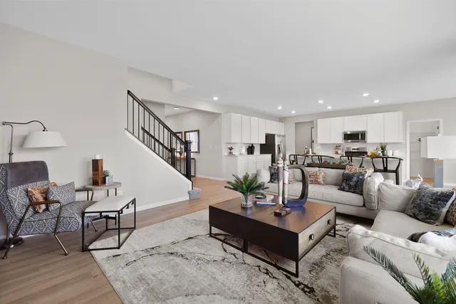a living room with furniture kitchen view and a wooden floor