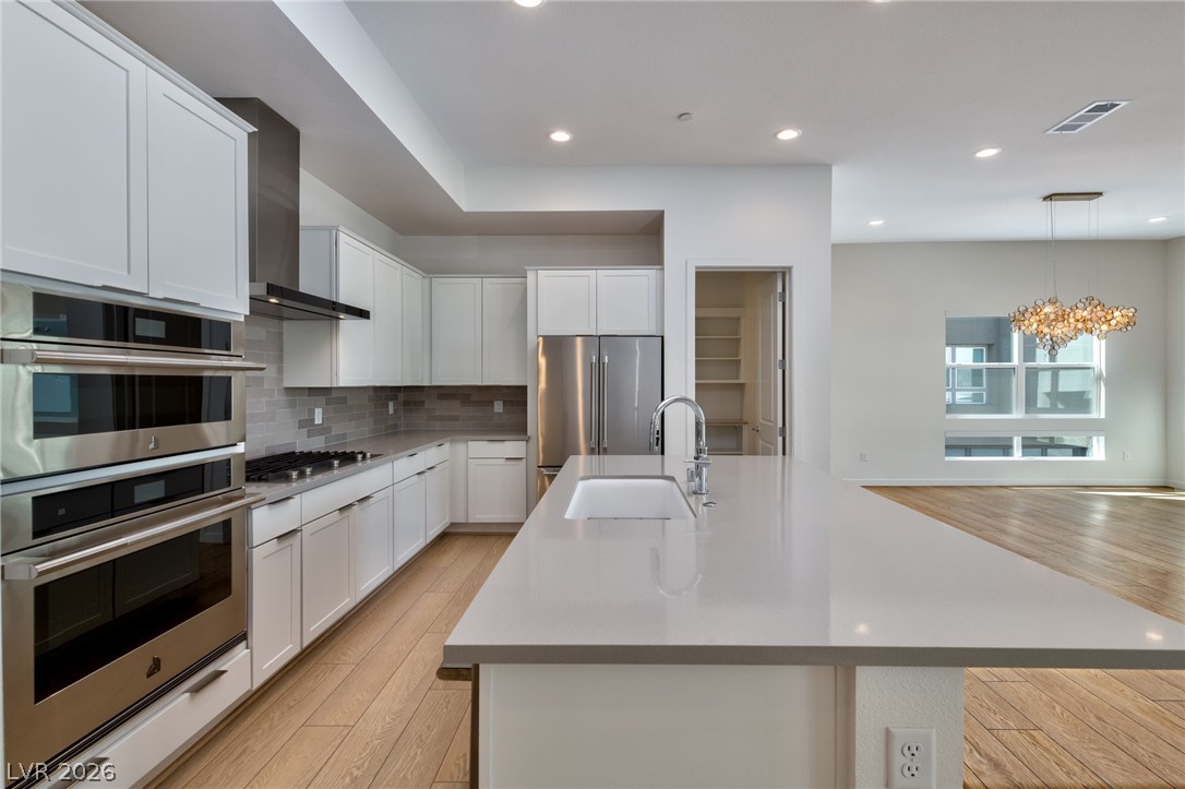 3327 Esker Rdg Avenue Henderson, NV 89044 - Photo 5 of 24 Culinary aspirations thrive in this kitchen, boasting pristine white cabinetry and gleaming JenaAir, Thermador stainless steel appliances.