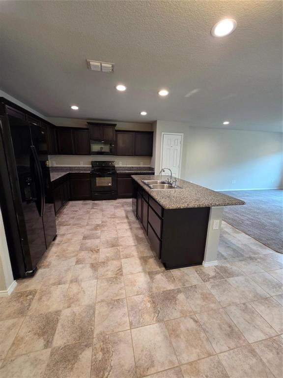 7504 Boat Wind Road Fort Worth, TX 76179 - Photo 9 of 17 a living room with stainless steel appliances kitchen island granite countertop a sink and cabinets
