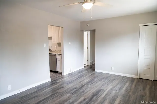 an empty room with wooden floor and a ceiling fan