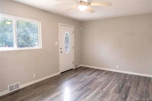 a view of an empty room with wooden floor and a window