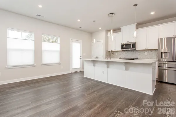 a kitchen with stainless steel appliances granite countertop a sink a stove a refrigerator and white cabinets