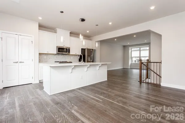 a view of kitchen with microwave a refrigerator and wooden floor
